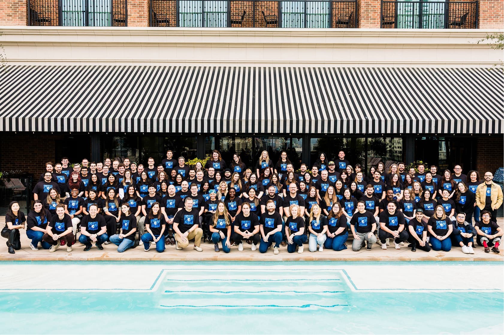 Group photo of the CertifID team standing and kneeling outside a modern building